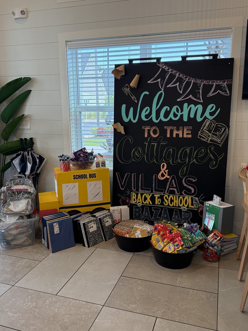 Back-to-School Bazaar display with donated school supplies, handmade school bus, and hand-lettered event backdrop